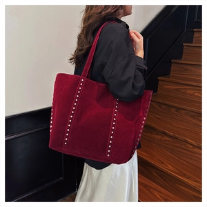 Macro shot of dark red suede tote bag featuring silver studs and leather shoulder strap