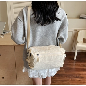 Detailed view of beige wrinkled nylon messenger bag with adjustable strap and zip pocket