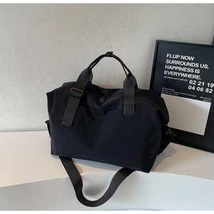 Detail of black nylon travel bag featuring reinforced handles and adjustable shoulder strap