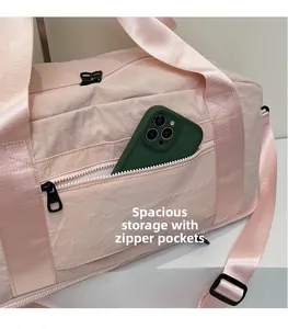 Detail of light pink travel bag showing front zipper pocket with a smartphone inside