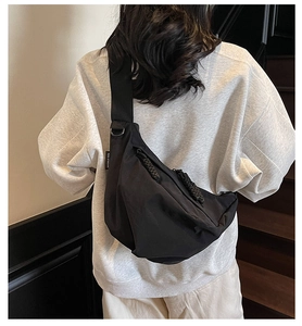Detailed back view of a black crescent nylon crossbody bag worn by a model