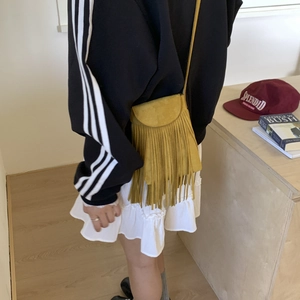 Bohemian mustard yellow suede crossbody bag with long tassels shown on a model
