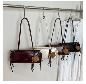 Detail view of four baguette bags in burgundy, white, brown and black with bear charms