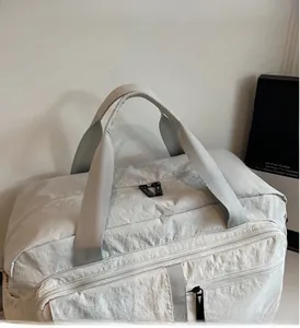 Detail of light grey travel bag with reinforced handles and durable nylon texture