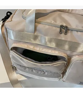 Dettaglio della tasca frontale con zip della borsa da viaggio beige con spazio per cellulare