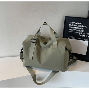 Close-up of olive green nylon travel bag with brand lettering and detachable shoulder strap