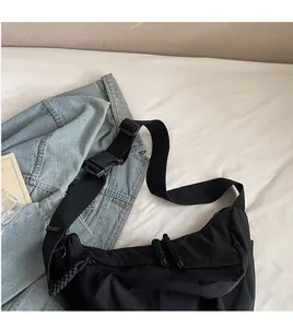 Detail of black nylon dumpling bag featuring adjustable wide strap and woven zipper puller