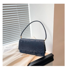 Detail of navy blue snakeskin textured handbag with gold hardware and arched handle