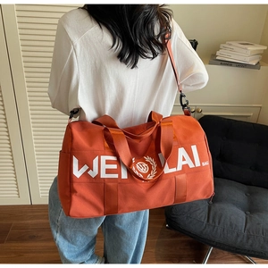 Orange gym duffel bag with white logo carried by model in a minimalist home setting