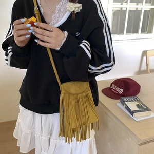 Detail of yellow faux suede crossbody bag with long tassels on a stylish outfit