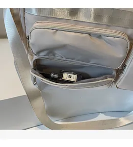 Dettaglio borsa da viaggio beige con tasche multiple a zip per organizzare lo spazio