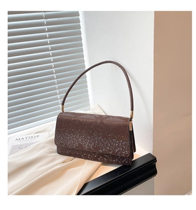 Detailed view of dark brown snake-pattern texture on a vintage leather handbag