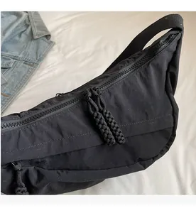 Detail of smooth double zippers with black woven cords on a nylon dumpling crossbody bag