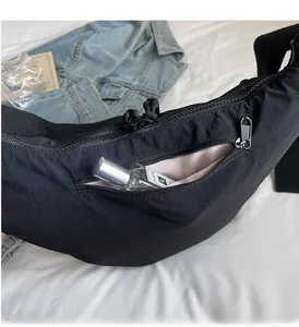 Detail of the black nylon crossbody bag showing the front zipper pocket and ample storage space