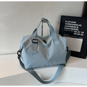 Detail of light blue waterproof travel duffel bag featuring Wellalbag logo and side pocket