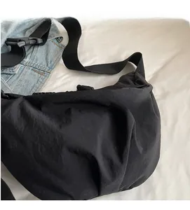 Close-up of soft pleated nylon crossbody bag with black webbing strap and buckle