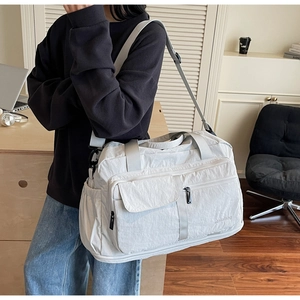 Detail of a large light grey travel bag showing lightweight nylon fabric and zippers