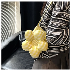 Détail du sac bandoulière en forme de fleur à carreaux jaunes porté sur un haut rayé
