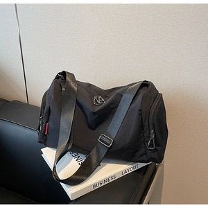 Detailed view of black nylon sports travel bag with double zippers and adjustable strap