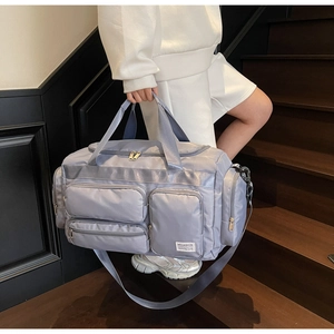 Dettaglio borsa da viaggio grigio-blu con tasche multiple a cerniera e tracolla larga