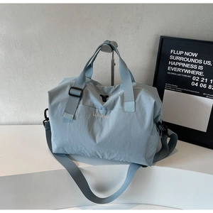 Close-up of light blue travel bag with Wellalbag embroidery and adjustable shoulder strap