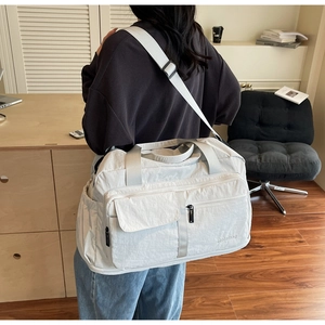 Detail of a large waterproof beige gym bag with shoulder straps worn by a model