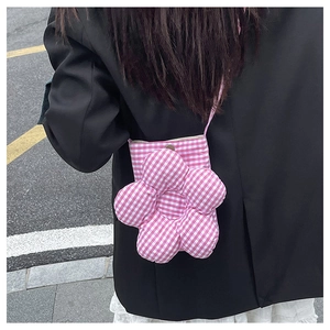 Détail d'un mini sac bandoulière à carreaux roses avec une grande fleur sur un blazer