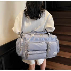 Dettaglio di una borsa da viaggio in nylon lavanda con tasche multiple e tracolla regolabile