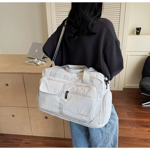 Spacious light grey travel bag worn by a model in a cozy indoor home office setting