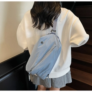 Detail of light blue nylon crossbody bag with adjustable wide strap on model back