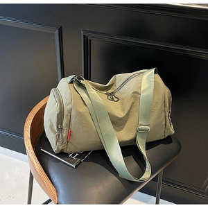 Detailed close-up of olive green canvas travel bag on black leather chair background