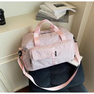 Detail of light pink travel bag with functional pockets and premium nylon texture