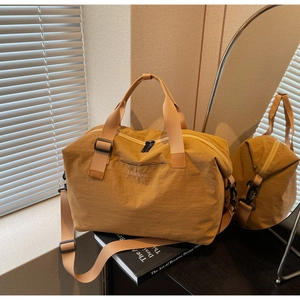 Detail of a ginger yellow travel bag with top handles and adjustable shoulder strap on counter