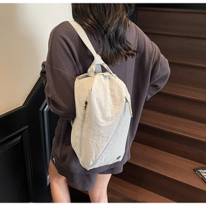 Detail of water-resistant off-white nylon backpack with front dual zipper pockets