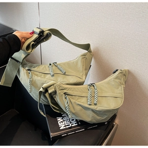 Detail of light green crescent crossbody bag with double zippers and adjustable strap