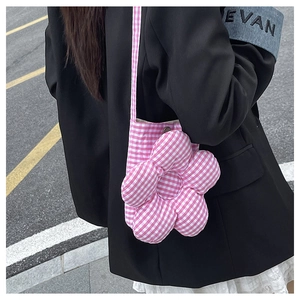 Détail du sac bandoulière en forme de fleur vichy rose porté avec un blazer noir