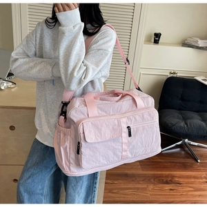 Detail view of pink large capacity travel bag with multiple pockets and shoulder strap