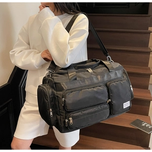 Pratica borsa da viaggio nera con tasche multiple indossata da modella su scale