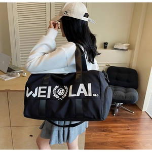 Detail of a large black duffel bag with WEILAI BAG logo and durable shoulder strap