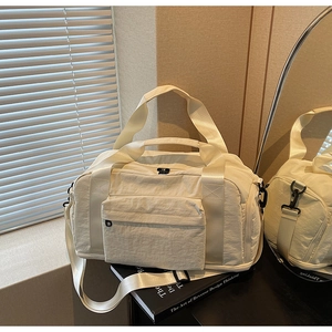 Detail of cream white travel duffel bag with dual handles and wide adjustable shoulder strap