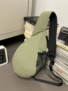 Light green nylon chest bag with mesh pocket and adjustable strap on a vintage desk