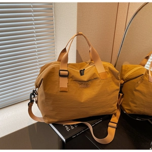 Detail view of mustard travel bag showing durable fabric, sturdy handles and shoulder strap
