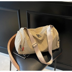 Detail of beige nylon duffle bag with adjustable wide strap and side zip pocket