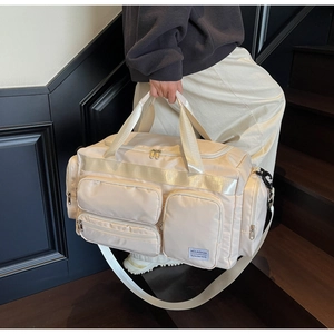 Dettaglio borsa da viaggio crema con design multi-tasca e manici rinforzati