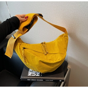 Detail of yellow canvas dumpling bag showing adjustable strap and woven zipper puller