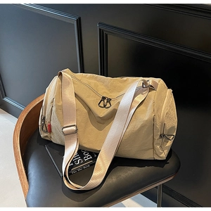 Detail of khaki water-resistant nylon travel bag with metal zippers on a modern chair