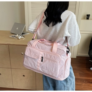 Back view of person carrying large pink nylon travel bag with functional pockets