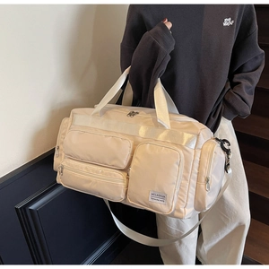 Dettaglio della borsa da viaggio color tè al latte con trama in nylon e tracolla