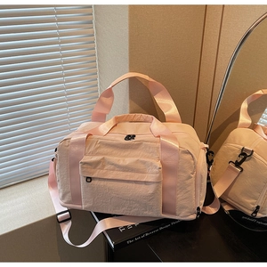Detail of light pink travel bag with durable nylon texture and adjustable shoulder strap