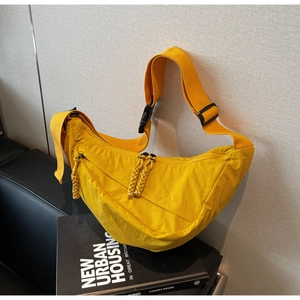 Detailed view of yellow crescent nylon bag with woven zipper pull on urban book prop